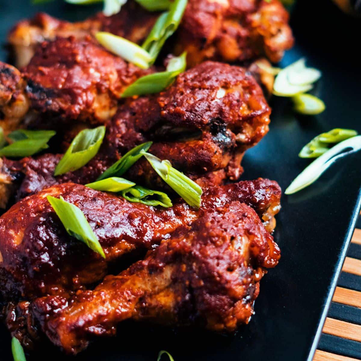 Slow Cooker BBQ Chicken Drumsticks on a black tray.