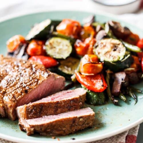 Garlic-Lime Steaks With Roasted Vegetables on a blue plate.