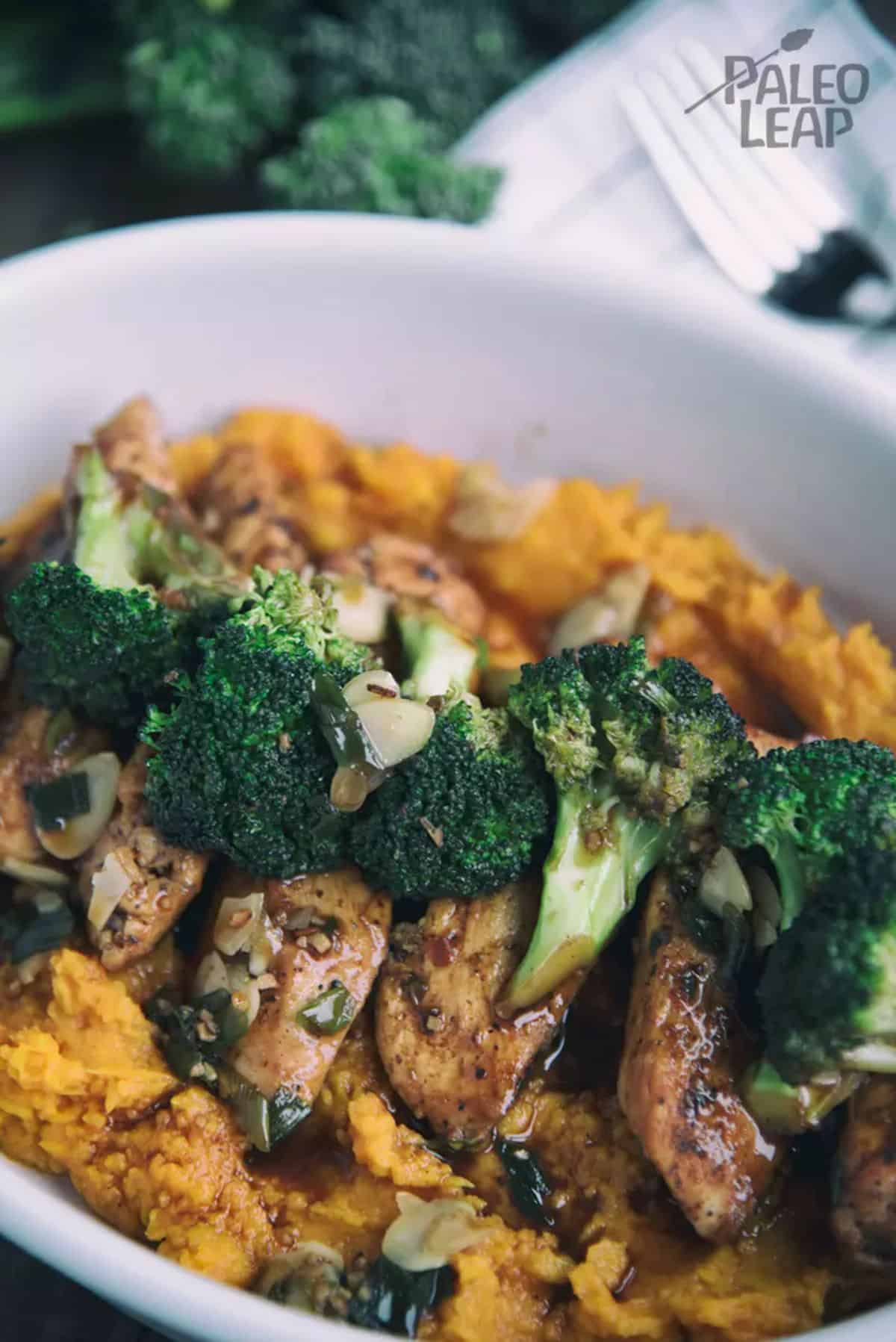 Glazed Chicken With Broccoli And Mashed Sweet Potatoes in a white bowl.