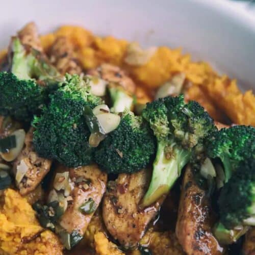 Glazed Chicken With Broccoli And Mashed Sweet Potatoes in a white bowl.