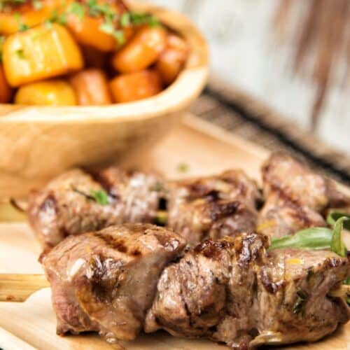 Skewered Lamb with Honey Glazed Carrots on a wooden cutting board.