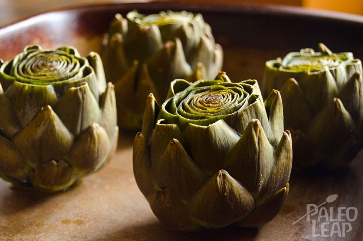 Slow-Cooked Garlic Artichokes on a wooden plate.