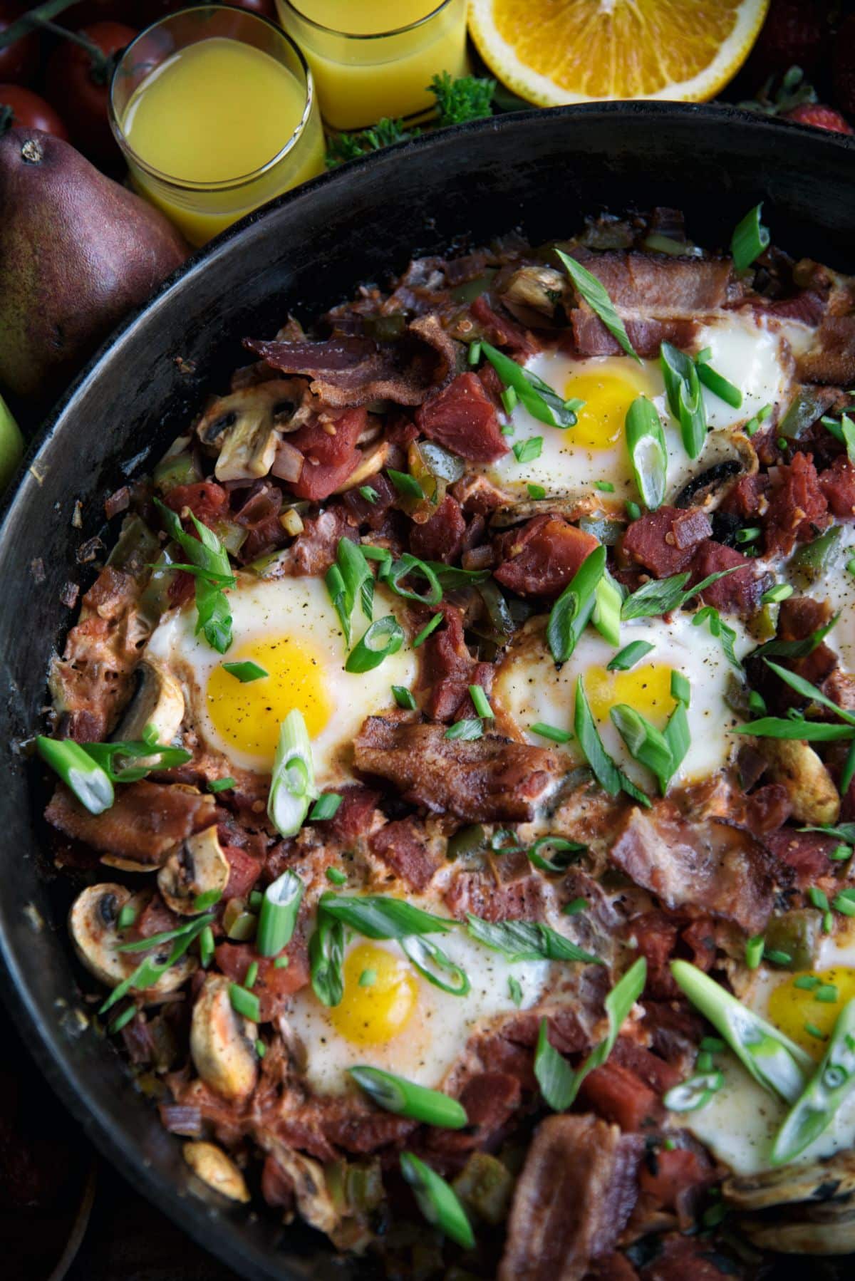 Skillet Eggs with Mushrooms And Bacon in a black pan.