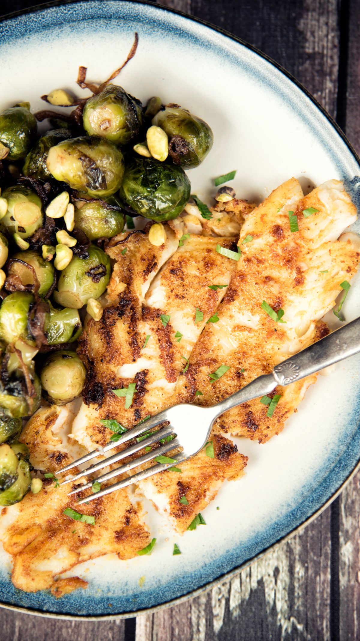 Grilled Seabass with Caramelized Brussels Sprouts on a plate with a fork.