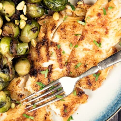 Grilled Seabass with Caramelized Brussels Sprouts on a plate with a fork.