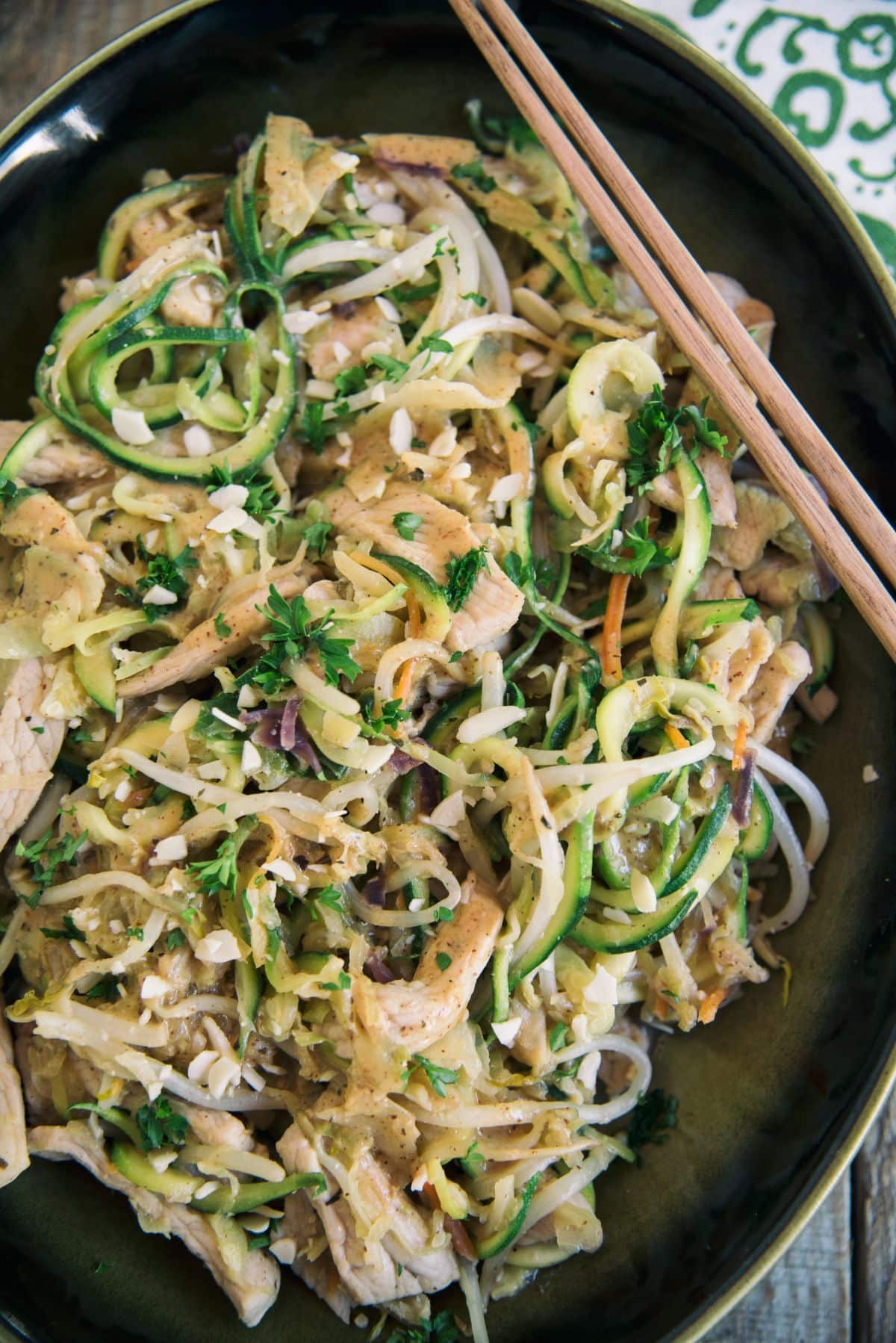 Almond Butter Chicken With Zucchini Noodles in a black pan with chopsticks.