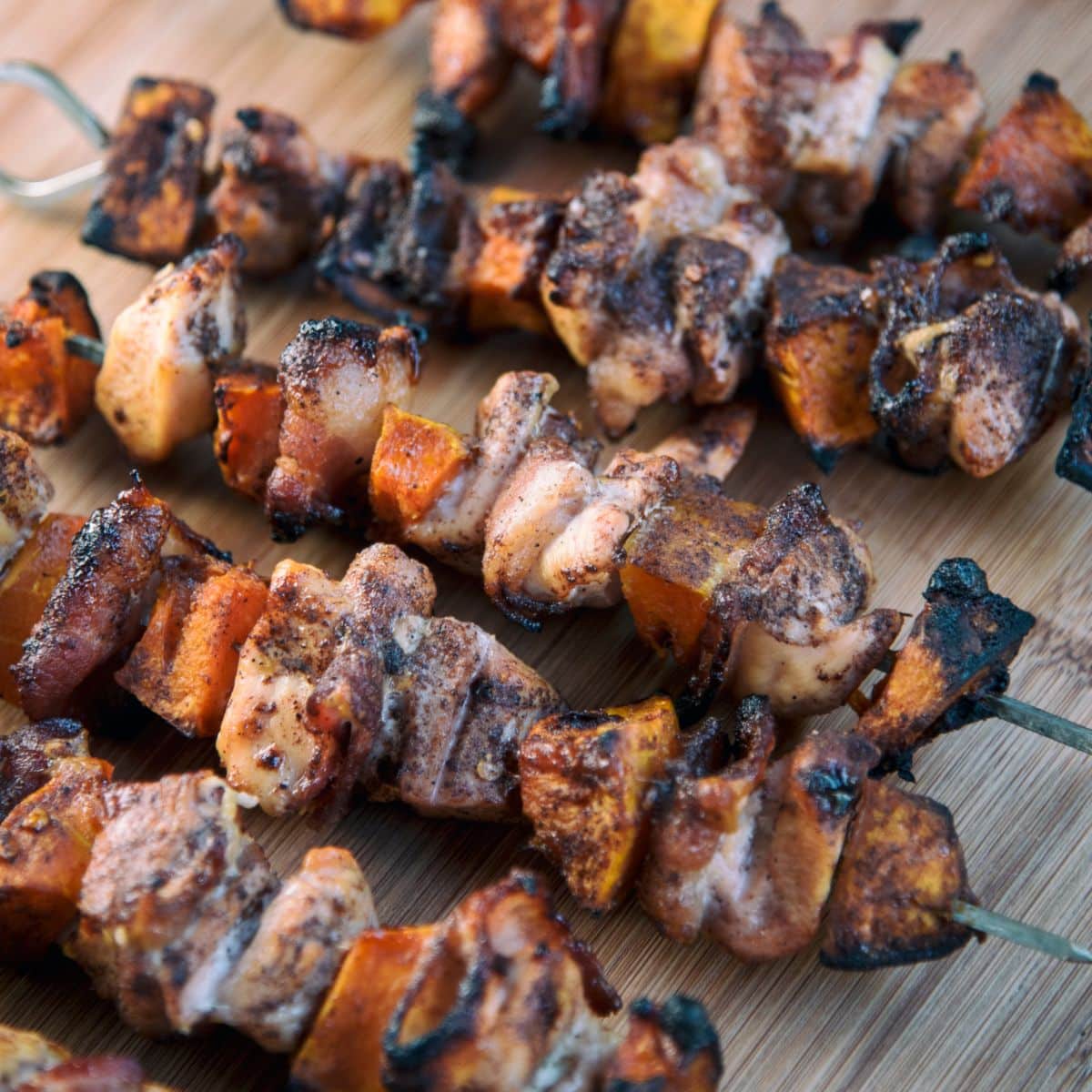 Chicken, Bacon, and Sweet Potato Skewers on a wooden board.