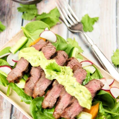 Steak Salad with Avocado Dressing on a wooden cutting board.