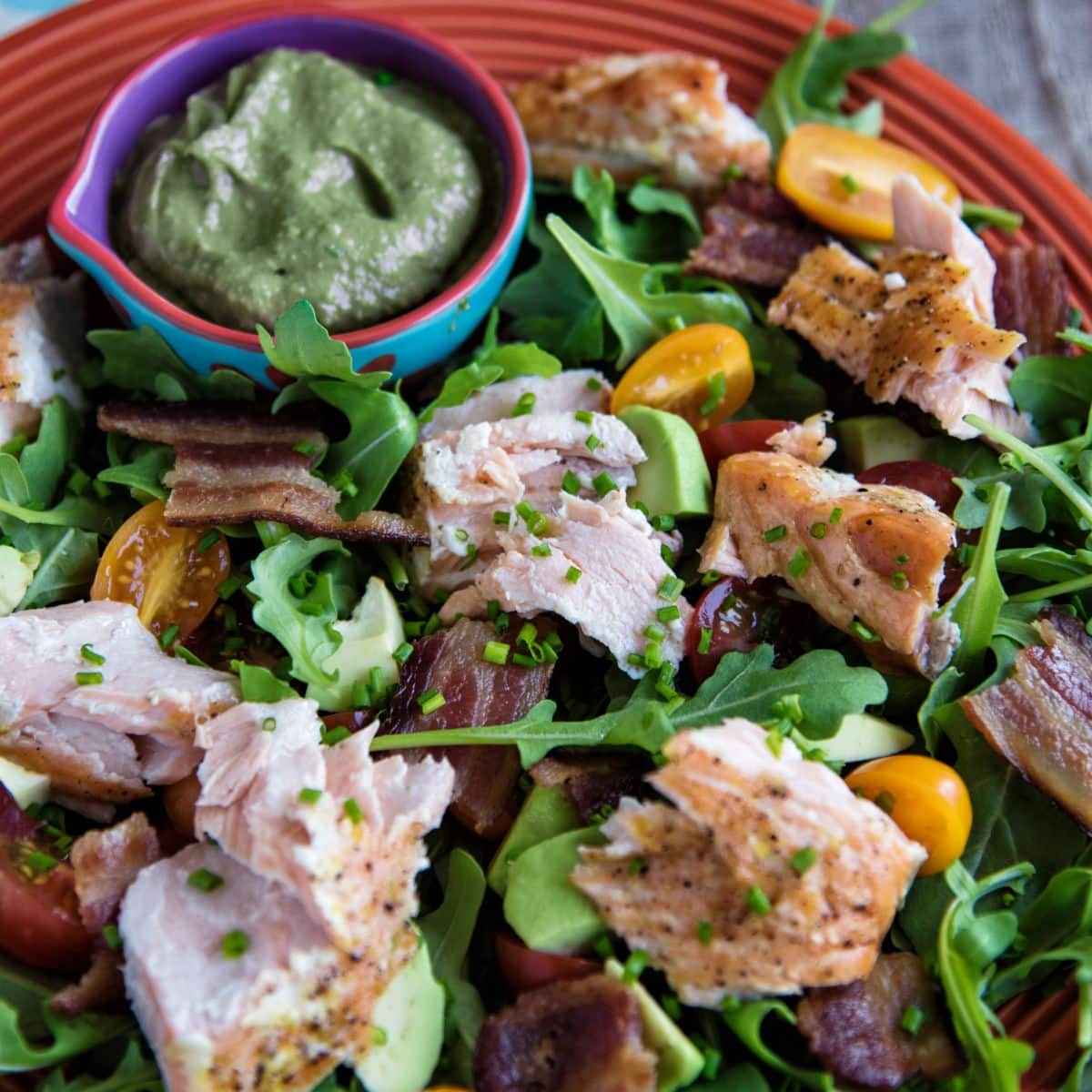 Salmon And Bacon Salad on a red plate.