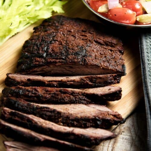 Flank Steak With Cherry Tomato Salad on a wooden cutting board.