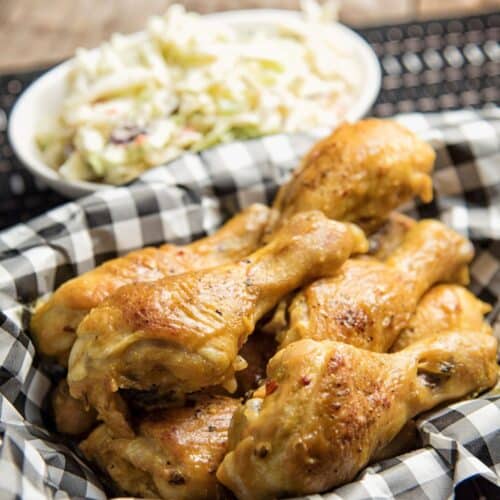 Mustard-Glazed Drumsticks With Creamy Coleslaw on a cloth wipe.