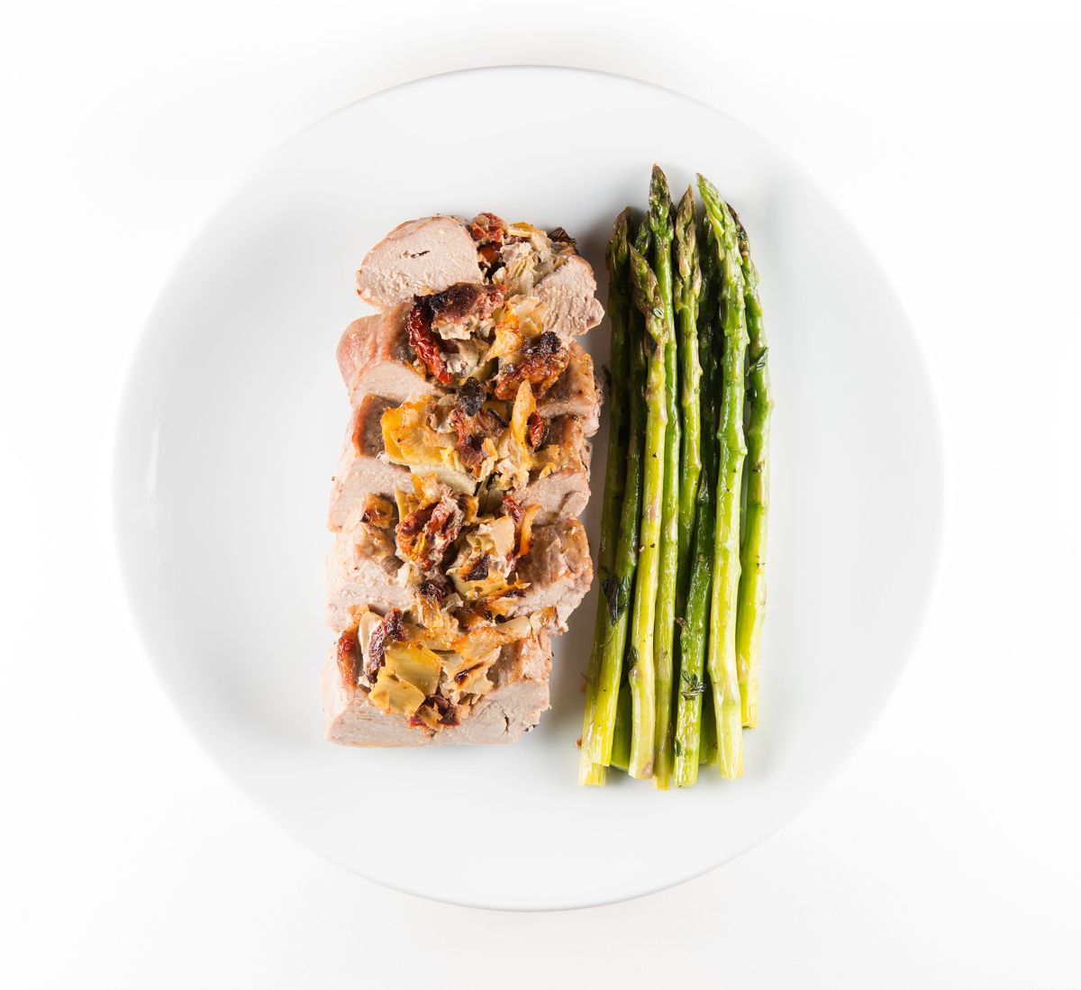 Stuffed Pork Tenderloin With Asparagus on a white plate.