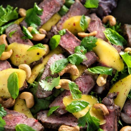 Sirloin Steak and Mango Salad on a black pan.