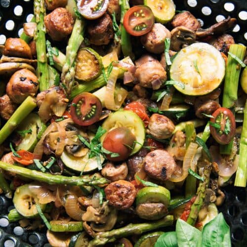 Grilled Sausages With Summer Veggies on a black grid.