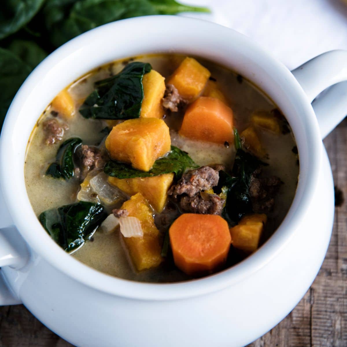 Sausage And Spinach Soup in a white pot.