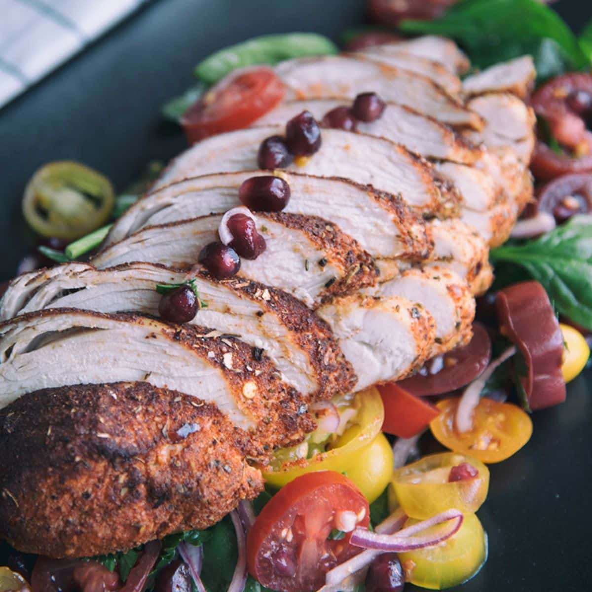 Chili-Rubbed Chicken With Tomato And Spinach Salad on a black tray.