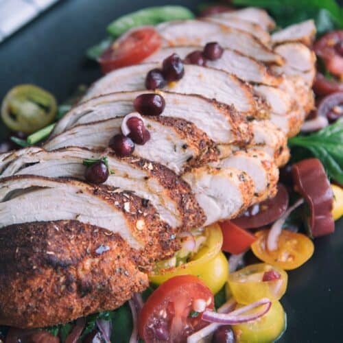 Chili-Rubbed Chicken With Tomato And Spinach Salad on a black tray.
