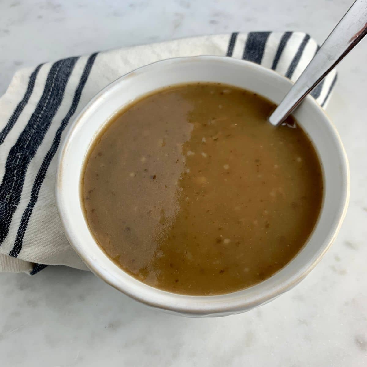 Paleo Turkey Gravy in a white plate with a spoon.