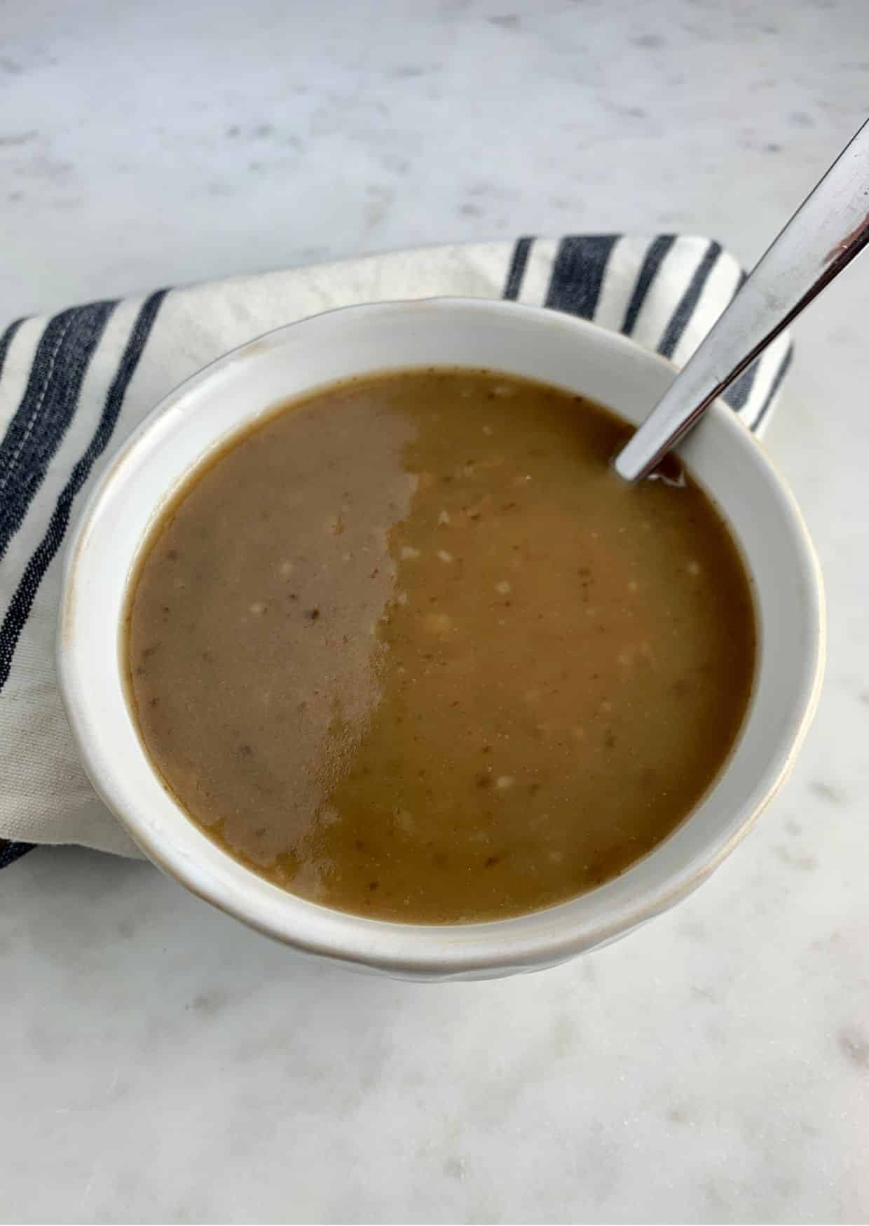 Paleo Turkey Gravy in a a white plate with a spoon.