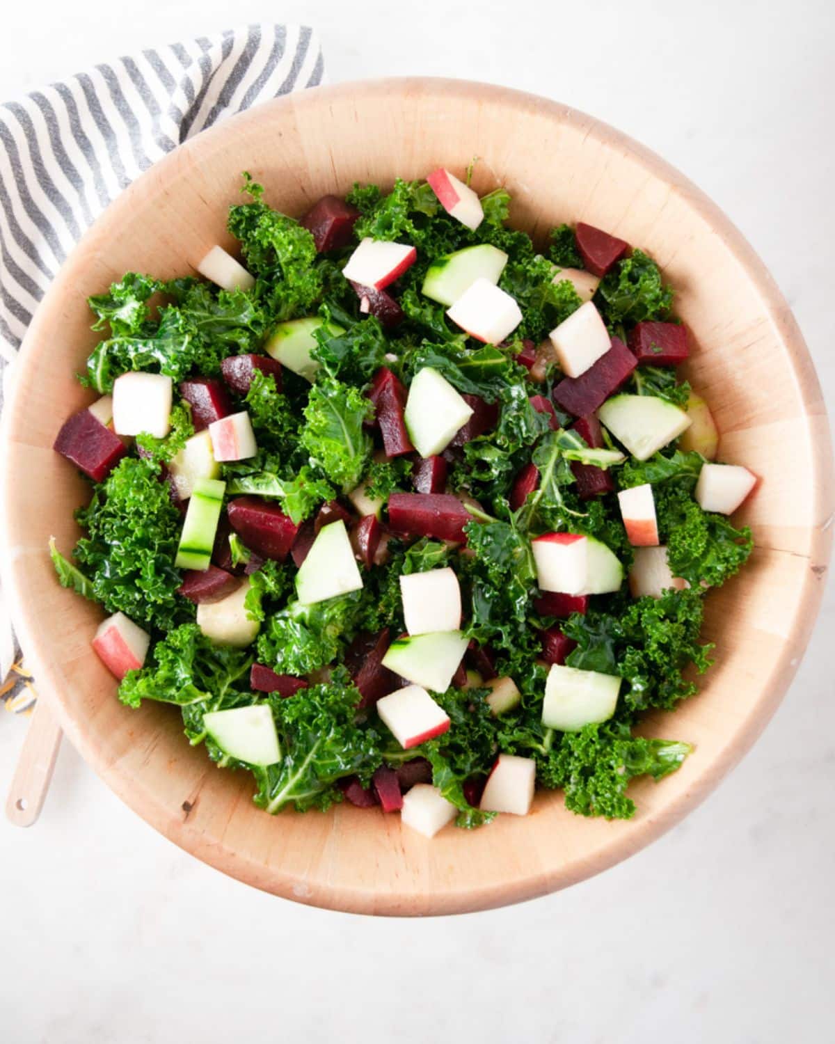 kale beet and apple salad served in a wooden bowl