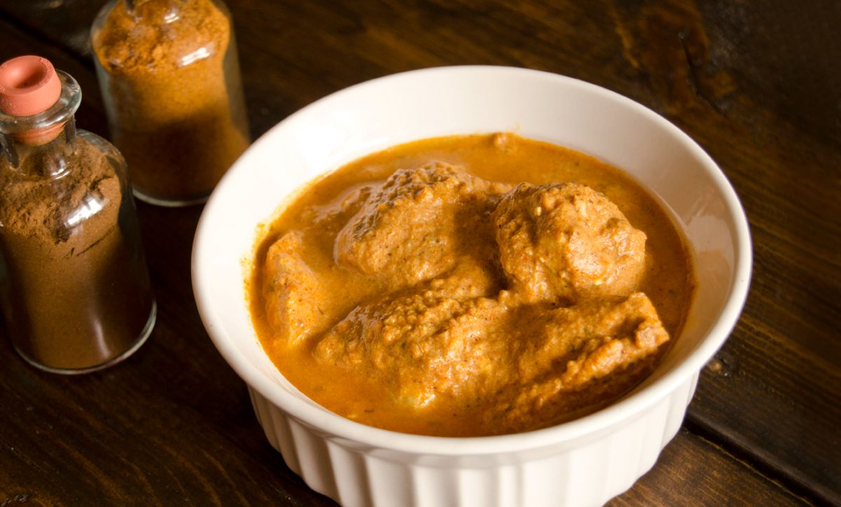 Butter chicken in a white bowl.