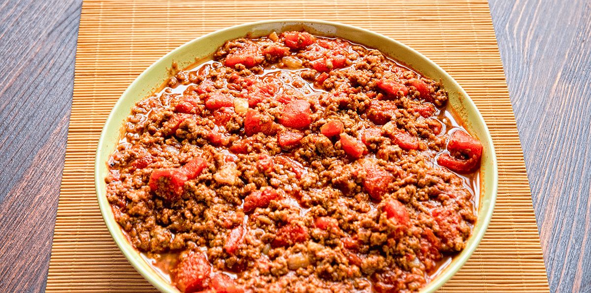 bean less Texas style chili in yellow bowl on bamboo placemat