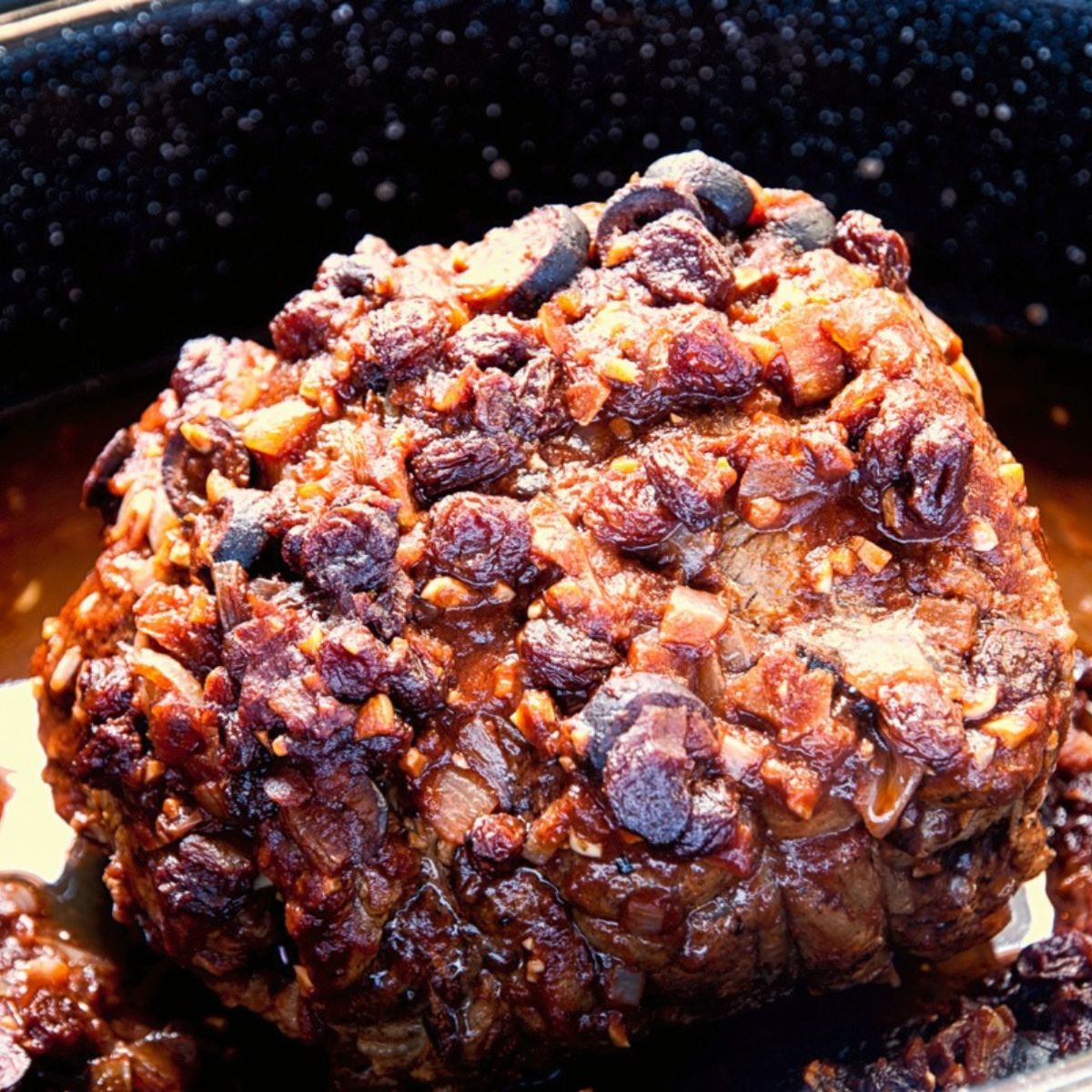 beef pot roast in pan with olives and raisins on top