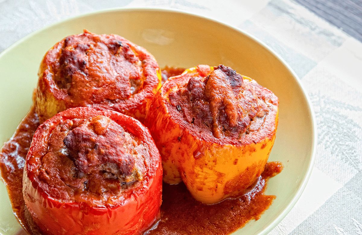 stuffed bell peppers with tomato sauce on top on yellow plate on white placemat