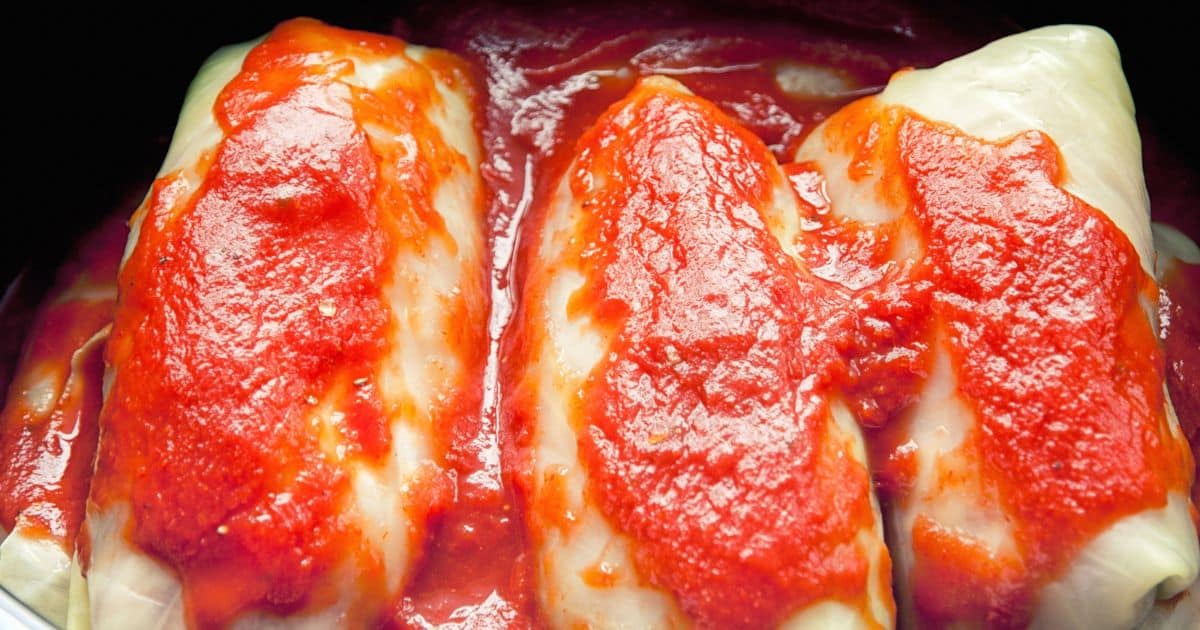 cabbage rolls topped by red sauce in crockpot