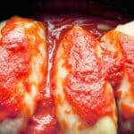 cabbage rolls topped by red sauce in crockpot