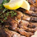 sliced leg of lamb with fresh thyme and lemon on top