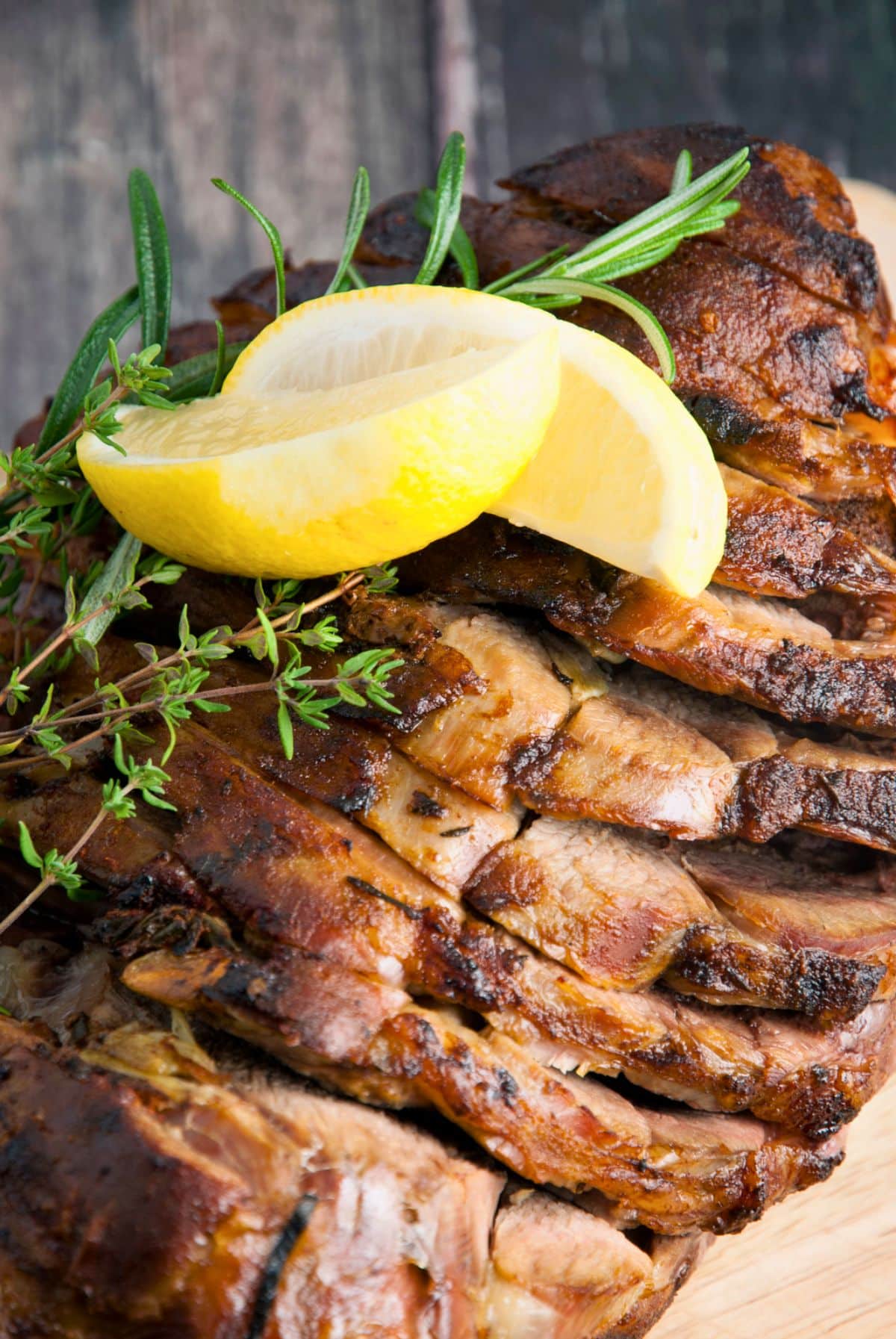 sliced leg of lamb with fresh thyme and lemon on top