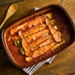 rectangular brown baking dish of bacon casserole with leeks in tomato sauce
