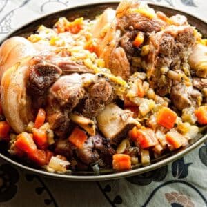 black bowl on table holding pork hocks and vegetables