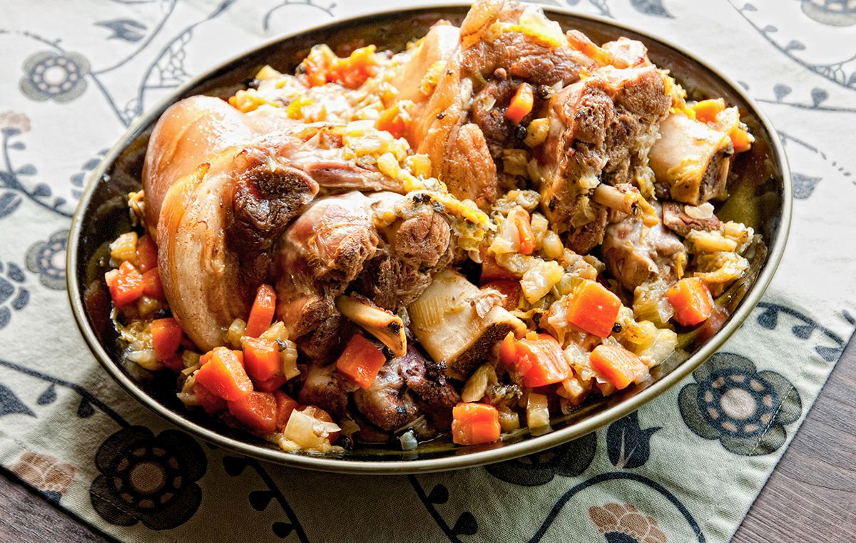 black bowl on table holding pork hocks and vegetables