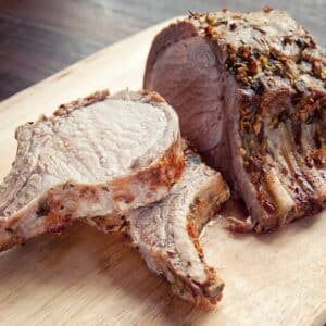 pork rib roast sliced on wood cutting board