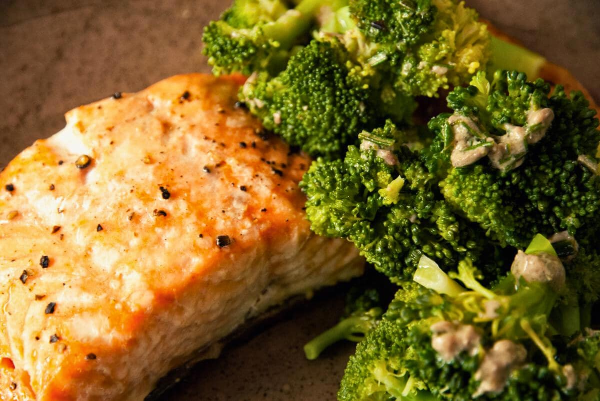wood plate of pan roasted salmon with broccoli and a rosemary dressing