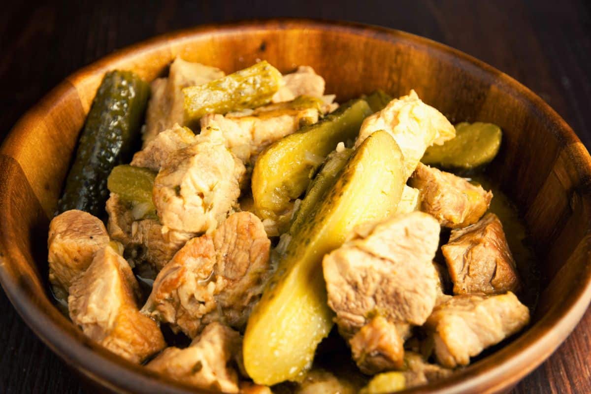 wooden bowl of pork stew with pickles
