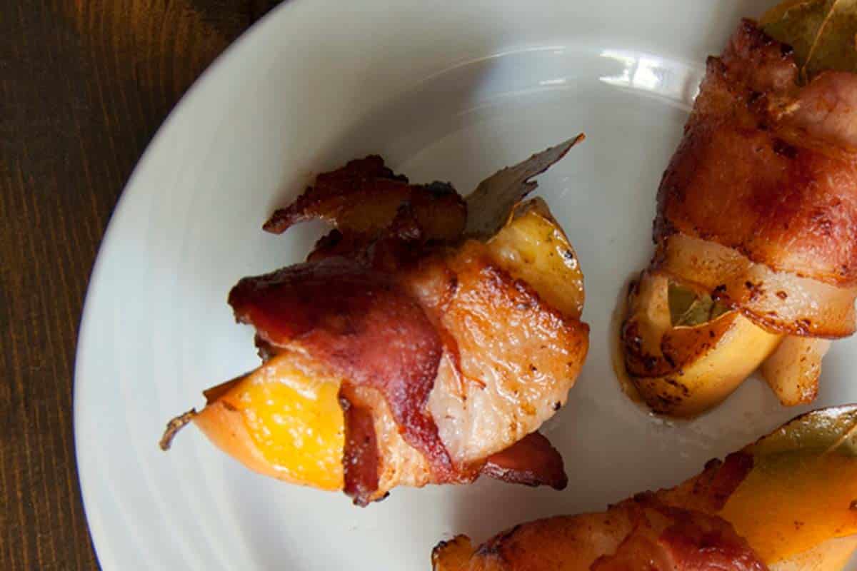 closeup of serving of Bacon Wrapped Peaches with Basil and Balsamic Vinegar on a white plate