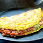 Guacamole and salsa omelet on a black plate