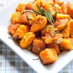 overhead view of a square bowl filled with Roasted Sweet Potatoes with Rosemary on a table