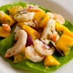 Shrimp and mango salad with vinaigrette on a white plate