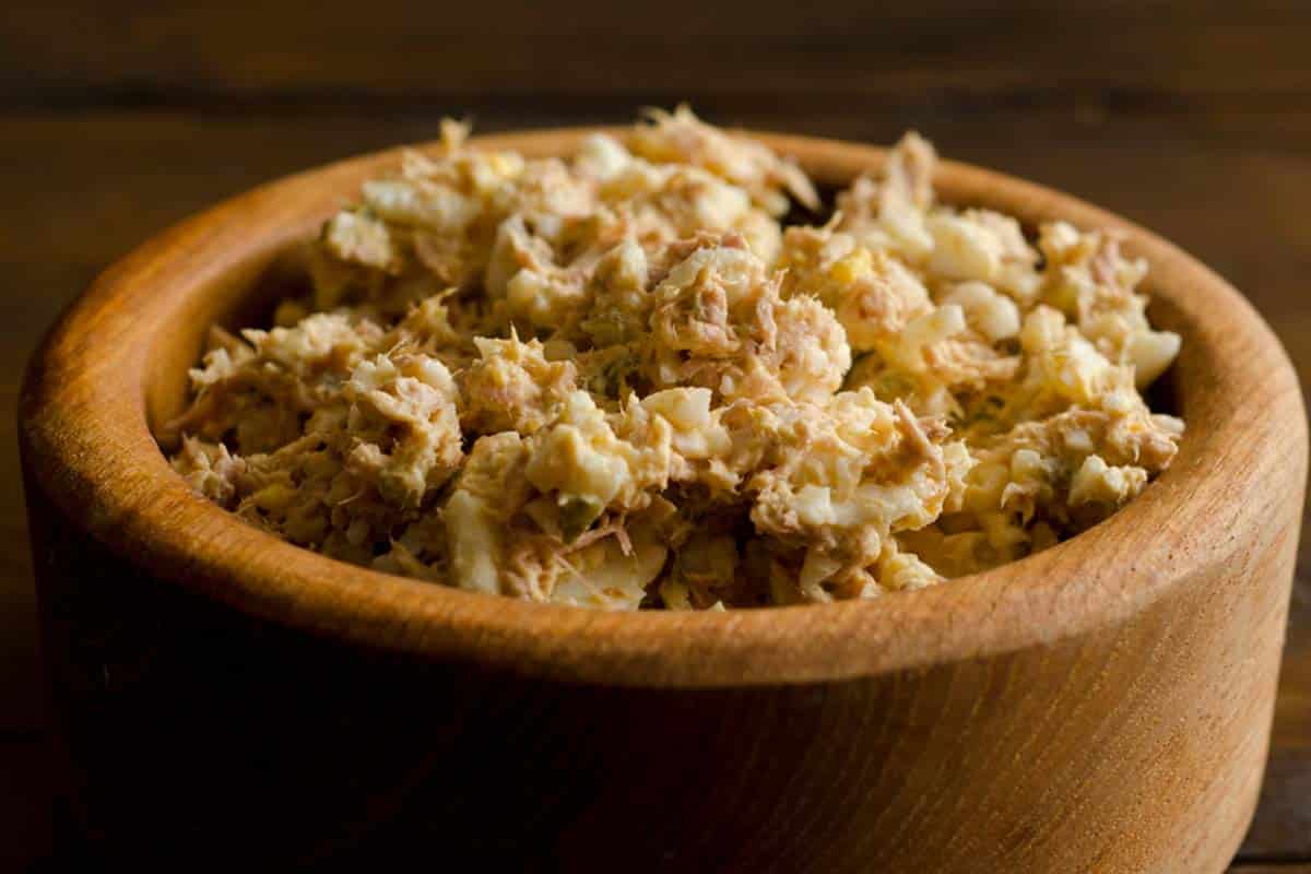 wooden bowl filled with Tuna and Egg Salad on a dark wood tbale