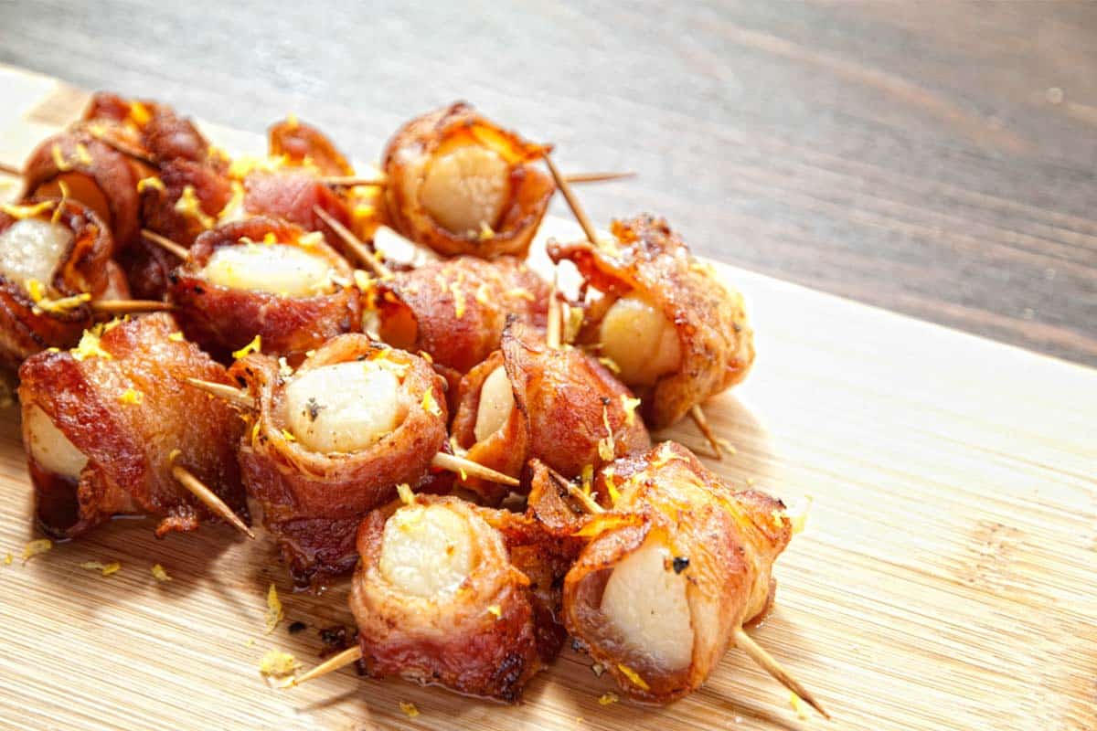 white plate full of scallops wrapped in bacon
