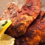 plate filled with blackened tilapia and sliced lemon