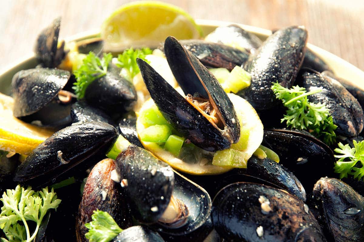 paleo-friendly curry mussels served with lemon wedges
