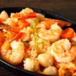 black bowl filled with shrimp and scallop paella stew