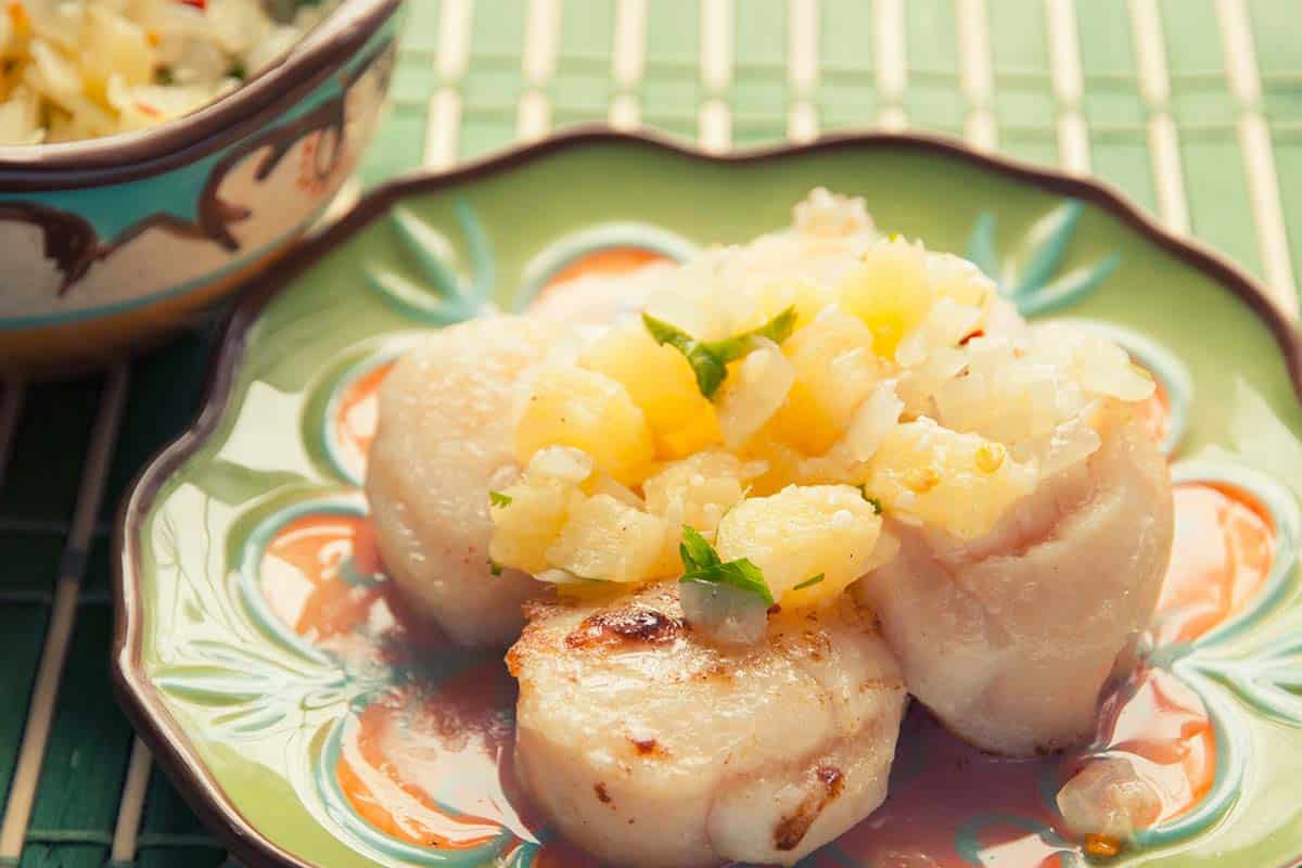 pineapple salsa topped scallops on a green plate