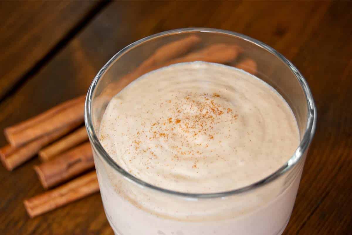 overhead view of a glass of Almond banana cinnamon smoothie on a wood table