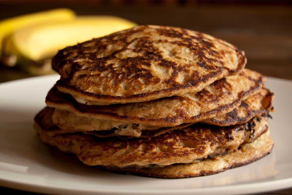 closeup of a stack of Almond banana pancakes on a white plate